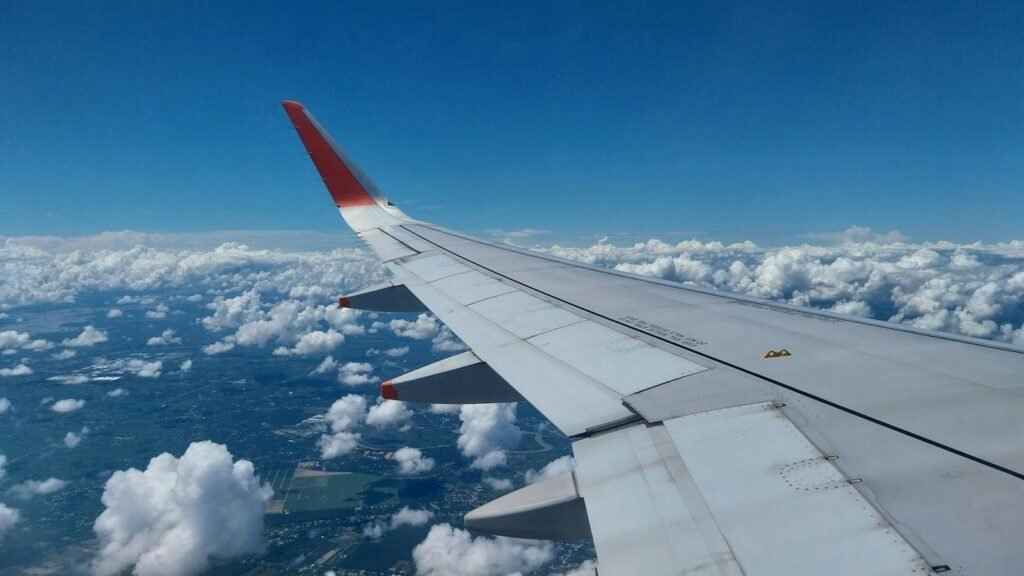 Airplane wing above the clouds under a blue sky