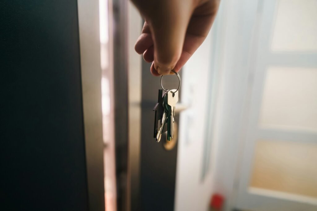 Hand holding a ring of keys in front of a partly open apartment door