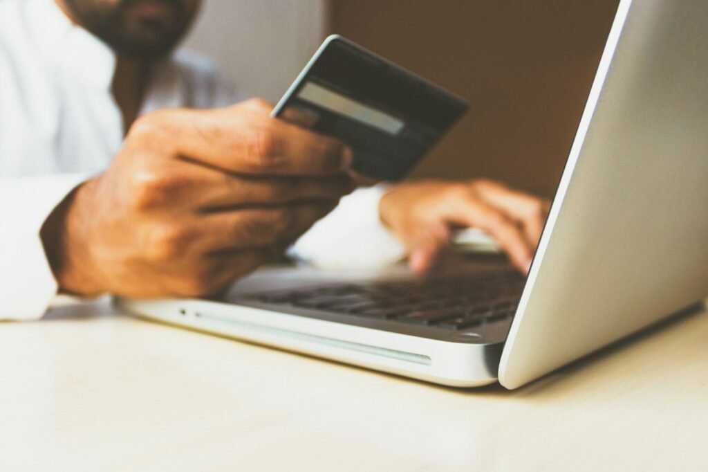 Hands holding a dark credit card while typing on a laptop to book travel