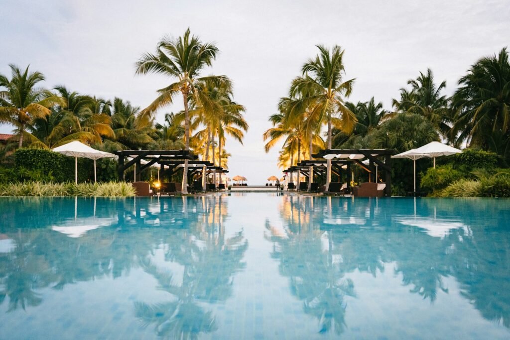 Infinity pool reflecting palm trees and white umbrellas at a tropical beach resort